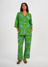 Woman wearing a green pajama set with blue fish pattern on a white background