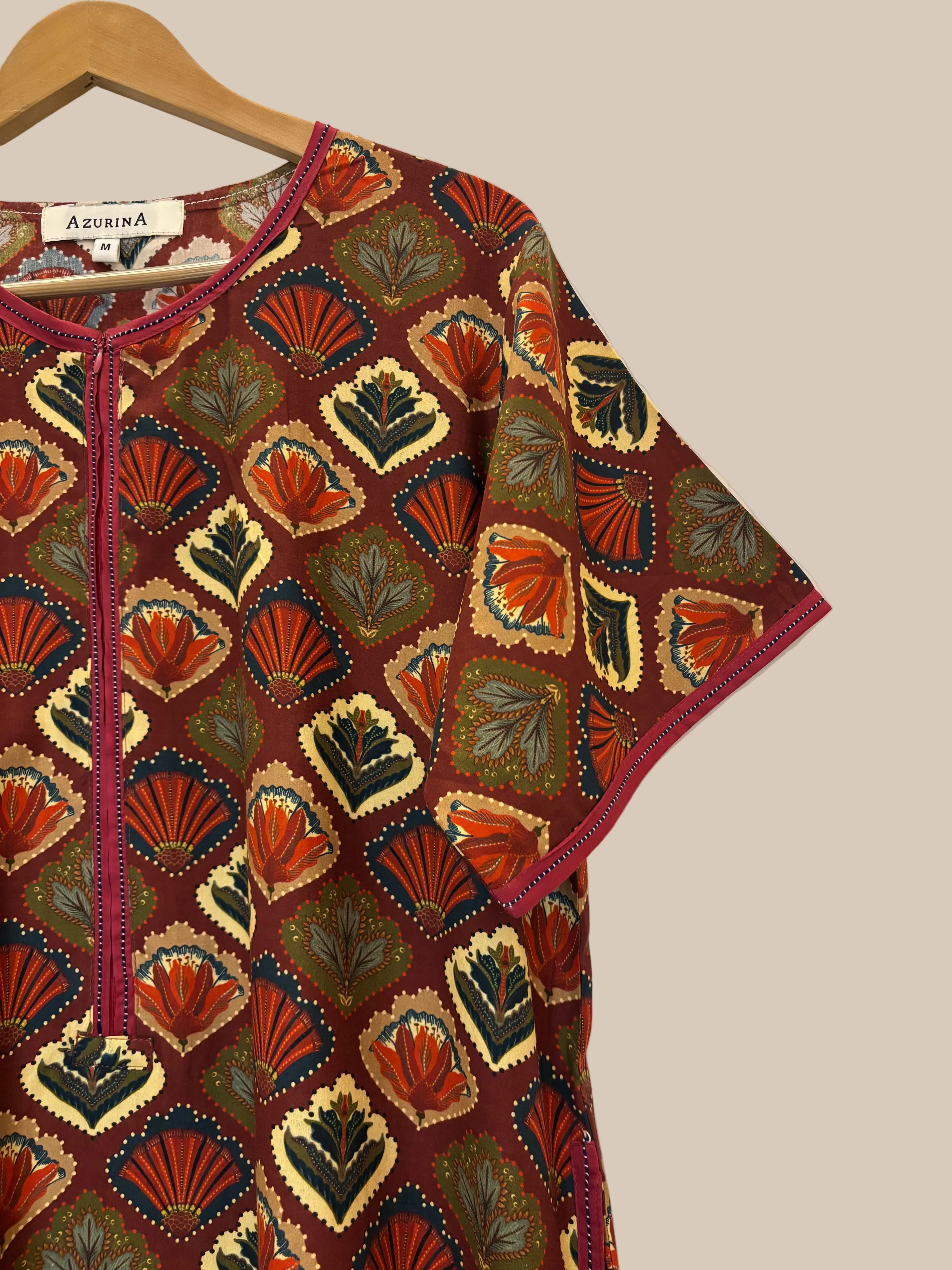 Colorful patterned nightgown on a hanger against a white wall