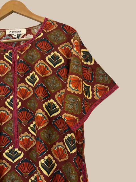 Colorful patterned nightgown on a hanger against a white wall